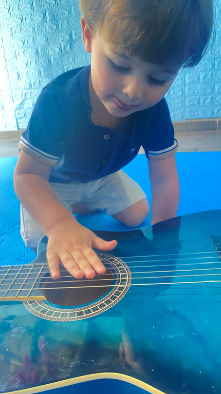Criança explorando as cordas de um violão